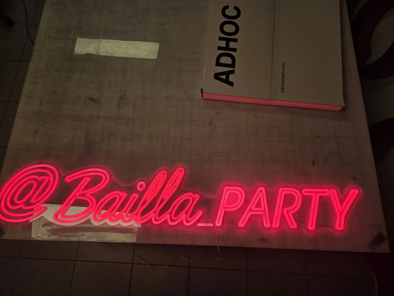 Czerwono-różowy neon LED z nazwą profilu Bailla Party na stole roboczym w pracowni, tuż po montażu taśmy LED Flex