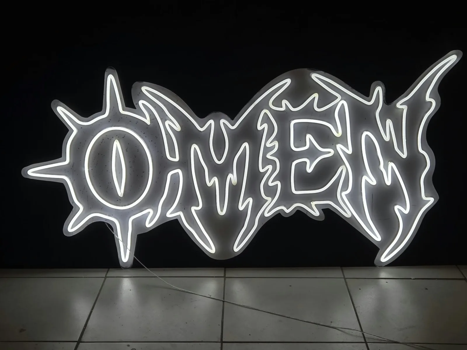 Biały neon LED „OMEN” w ostrym, metalowym stylu liter, wycięty po obrysie z przezroczystej pleksi